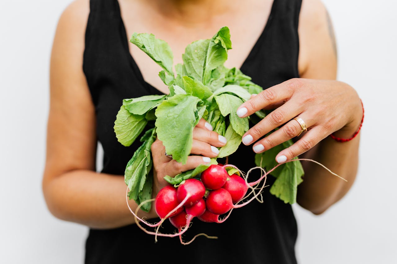 service-02 A person holding fresh radishes with vibrant green leaves against a white background.